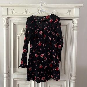 Black dress with pink floral pattern. Long sleeves.